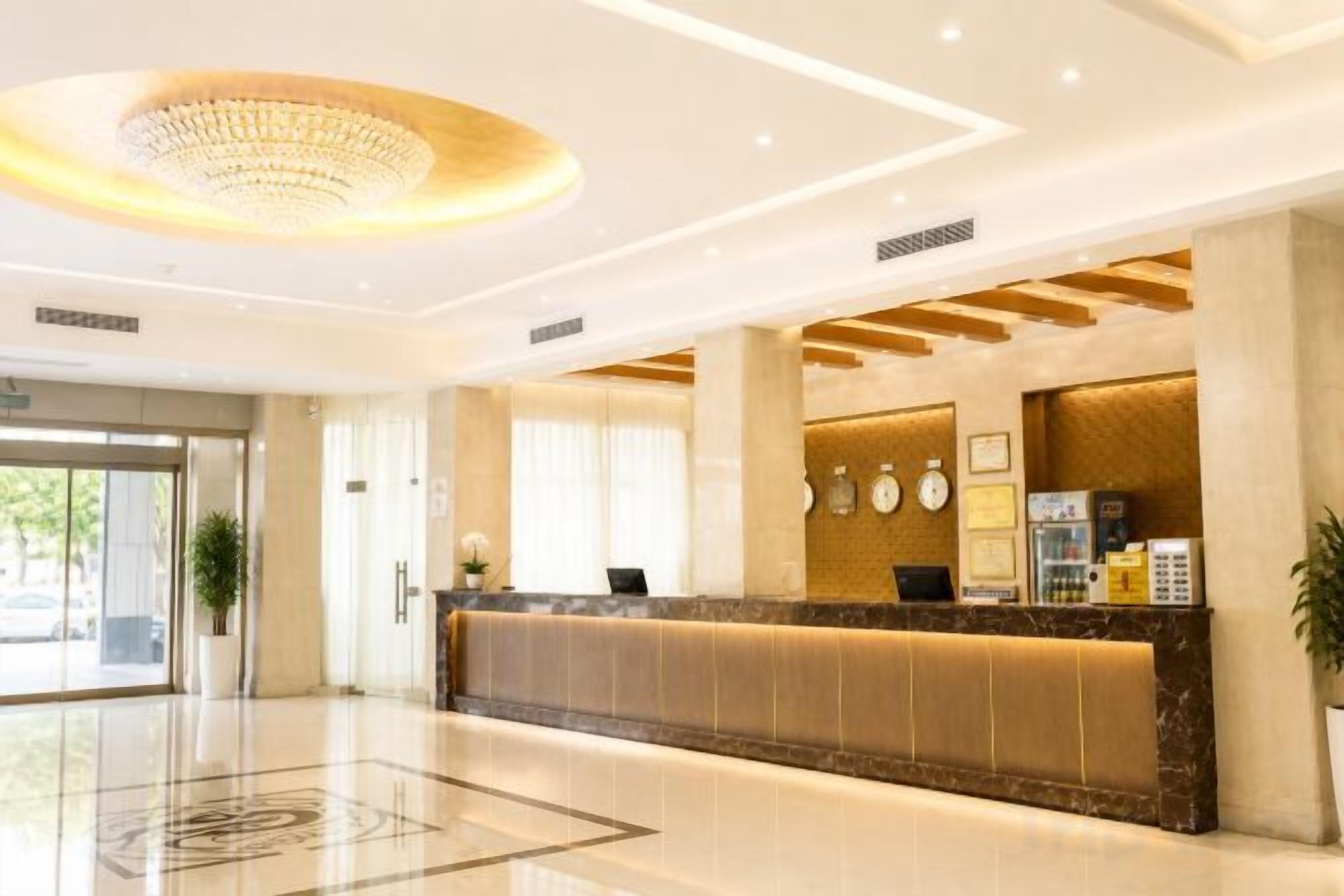 A hotel reception area with a marble counter, a chandelier, and a large window.