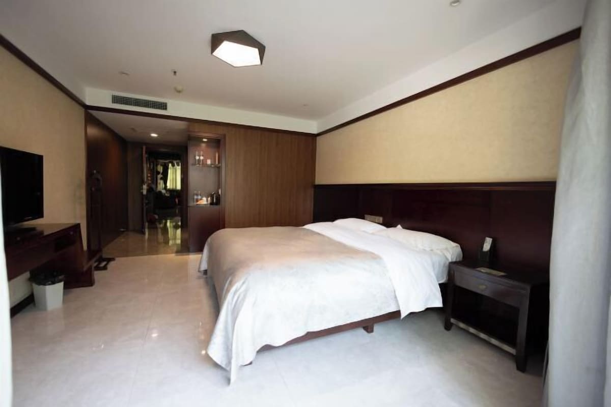 Ein Hotelzimmer mit Bett, Fernseher, Nachttisch und Kleiderschrank.