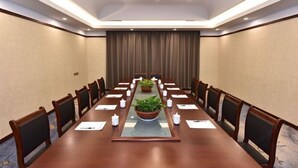 A conference room with a long table, chairs, potted plants, and a chandelier. - Dongsheng Hotel (Zouping)