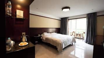 A hotel room with a bed, bedside table, and a view of the outdoors.