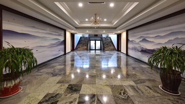 Eine großzügige Lobby mit Marmorboden, einem Chandelier und einer Treppe zu einer oberen Ebene.