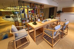 A cozy room with a wooden dining table, chairs, and a bookshelf. - Jinghu Hotel (Yuxi)