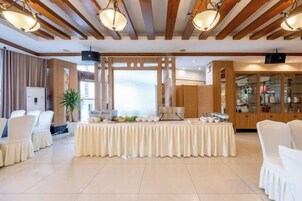 Un salón de banquetes con una larga mesa, sillas y una mesa de bufé.