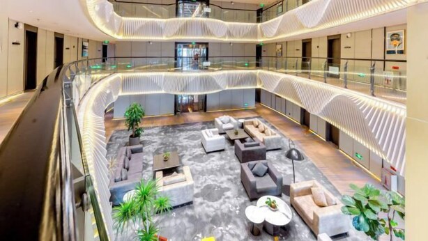 A modern atrium with a central seating area, multiple levels, and a glass railing.