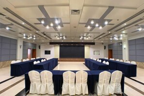 A conference room with long tables, chairs, a stage, and a projector screen. - Jinghu Hotel (Yuxi)