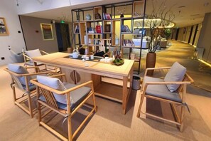 A room with a long wooden table, four chairs, a bookshelf, and a vase with branches. - Jinghu Hotel (Yuxi)