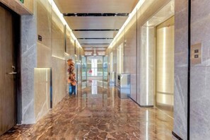 A modern hotel corridor with marble flooring, glass doors, and a central elevator. - Jinghu Hotel (Yuxi)