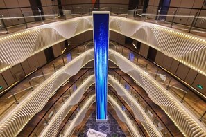 A modern atrium with a central vertical light feature, multiple levels of balconies, and a patterned floor design. - Jinghu Hotel (Yuxi)