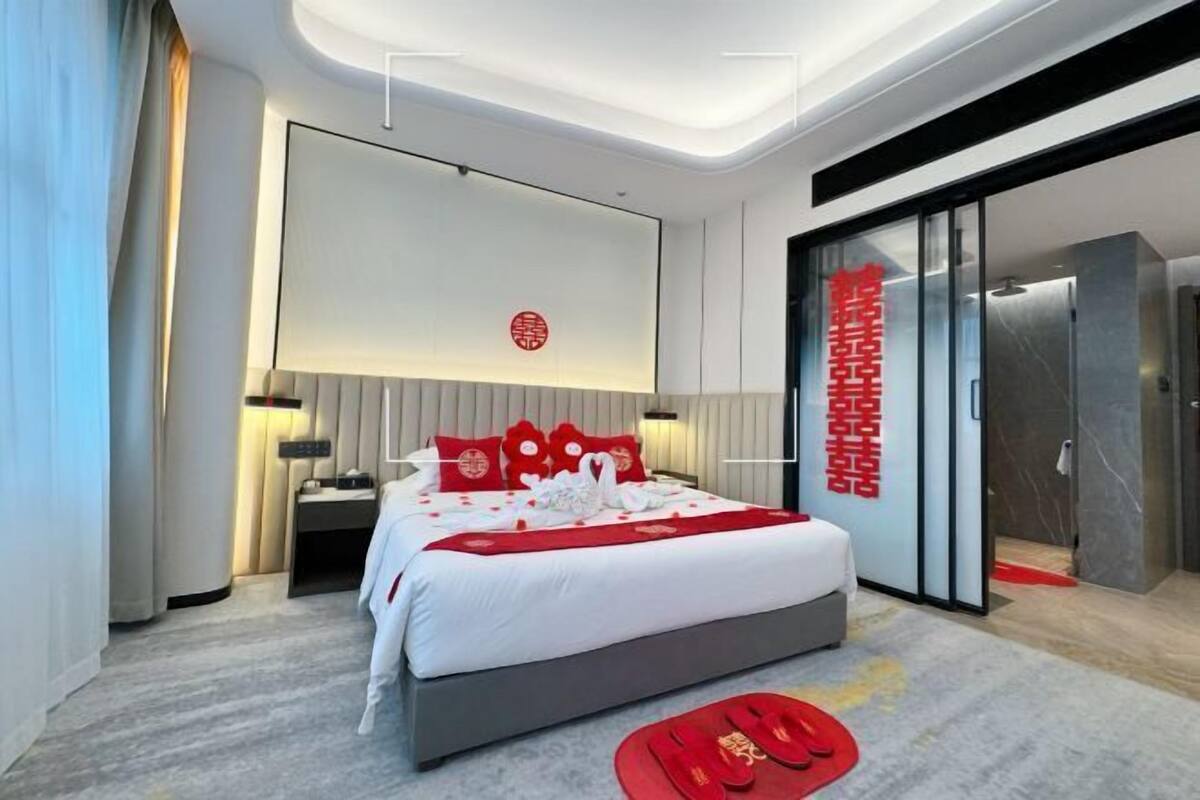 Una habitación de hotel moderna con una cama, mesitas de noche, un televisor de pared y una puerta corredera.