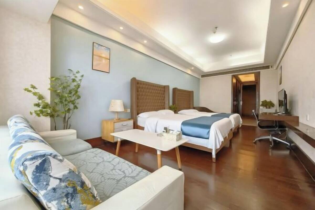 A hotel room with a bed, a sofa, a desk, and a chair.