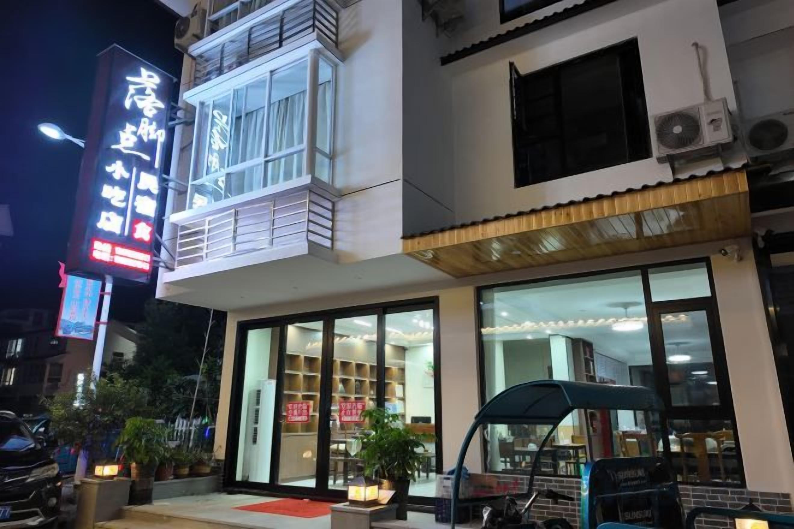 Un hotel con restaurante en la planta baja, amplias ventanas y un balcón.