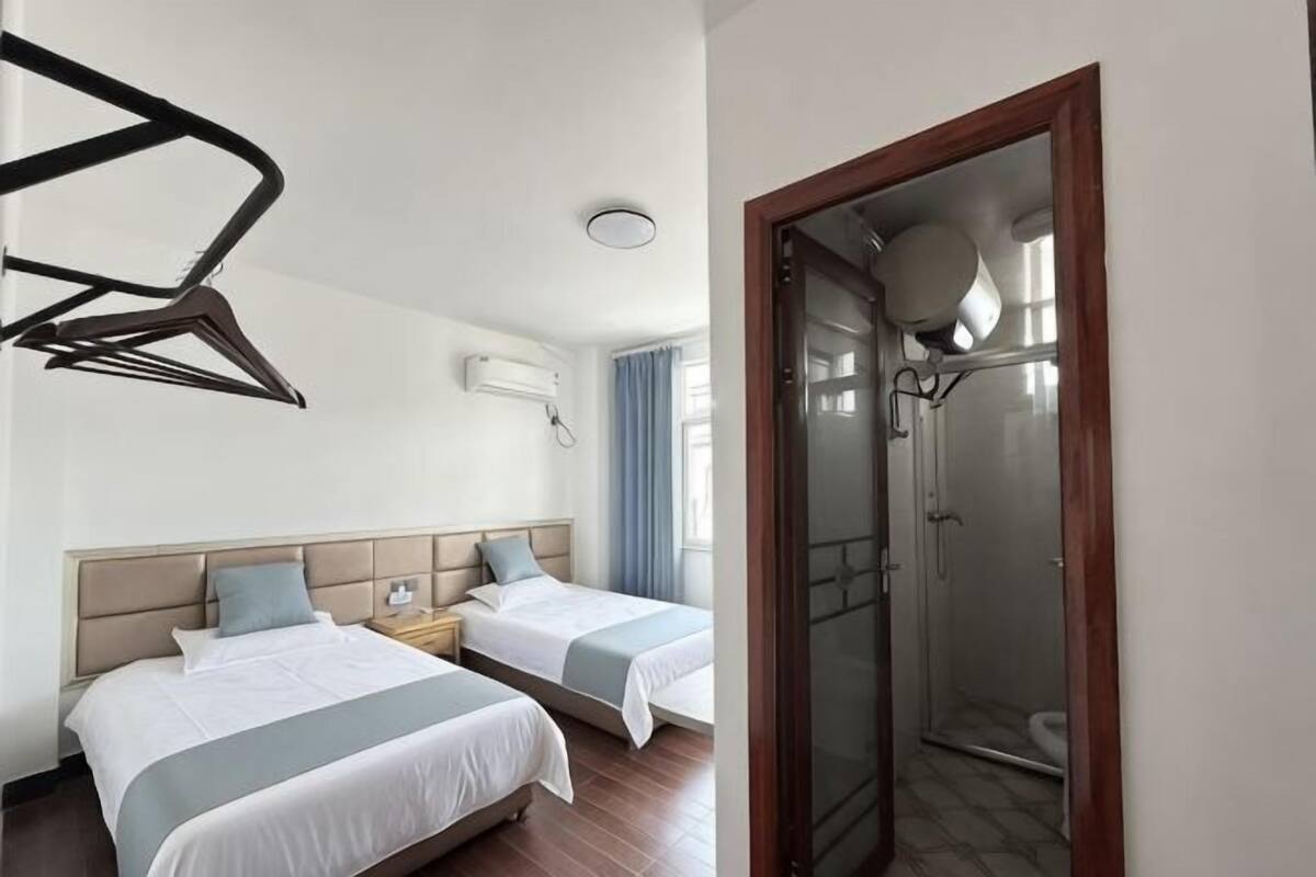 A hotel room with two beds, a shower, and a wooden door.