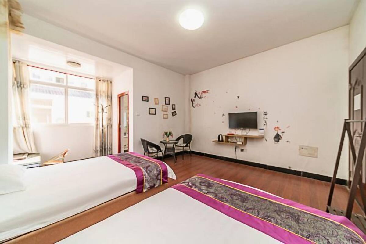 A room with two beds, a TV, a desk, and a chair.