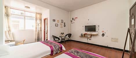 A room with two beds, a TV, a desk, and a chair.