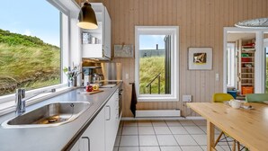 A modern kitchen with a large window, stainless steel sink, and wooden cabinets. - "Paaske" -  from the sea by Interhome (Ringkøbing)