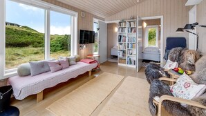 A cozy living room with a large window, a sofa, a bookshelf, and a dog. - "Paaske" -  from the sea by Interhome (Ringkøbing)
