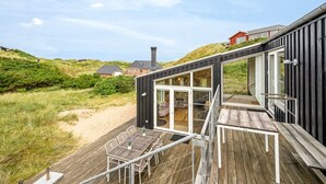 A modern house with a deck, large windows, and a view of the surrounding landscape. - "Paaske" -  from the sea by Interhome (Ringkøbing)