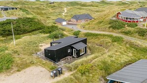 A coastal property with a modern black building, a red house with a white porch, and a sandy path leading to a dune. - "Paaske" -  from the sea by Interhome (Ringkøbing)