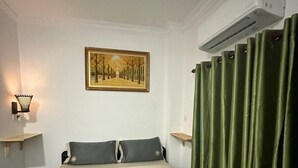 A hotel room with a bed, a painting on the wall, and a green curtain. - Green Ocean Lodge (Koh Rong)