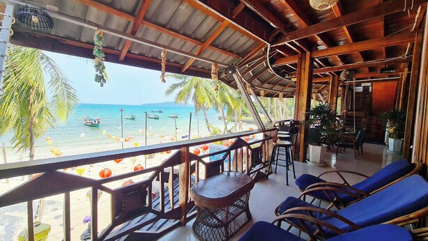 A beachside restaurant with a view of the ocean, wooden furniture, and a thatched roof. - Green Ocean Lodge (Koh Rong)