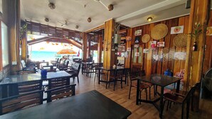 A restaurant with wooden walls and tables, a view of the sea, and various food items displayed on the walls. - Green Ocean Lodge (Koh Rong)