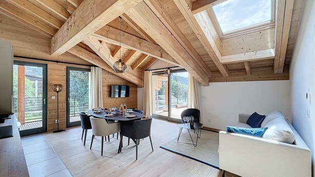 A modern interior with a wooden ceiling, a dining area with a table and chairs, a sofa, and large windows. - Cedrela-appartement-5/7pers-Centre station (Les Gets)