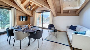 A modern interior with a dining area, a sofa, and a view of the outdoors. - Cedrela-appartement-5/7pers-Centre station (Les Gets)