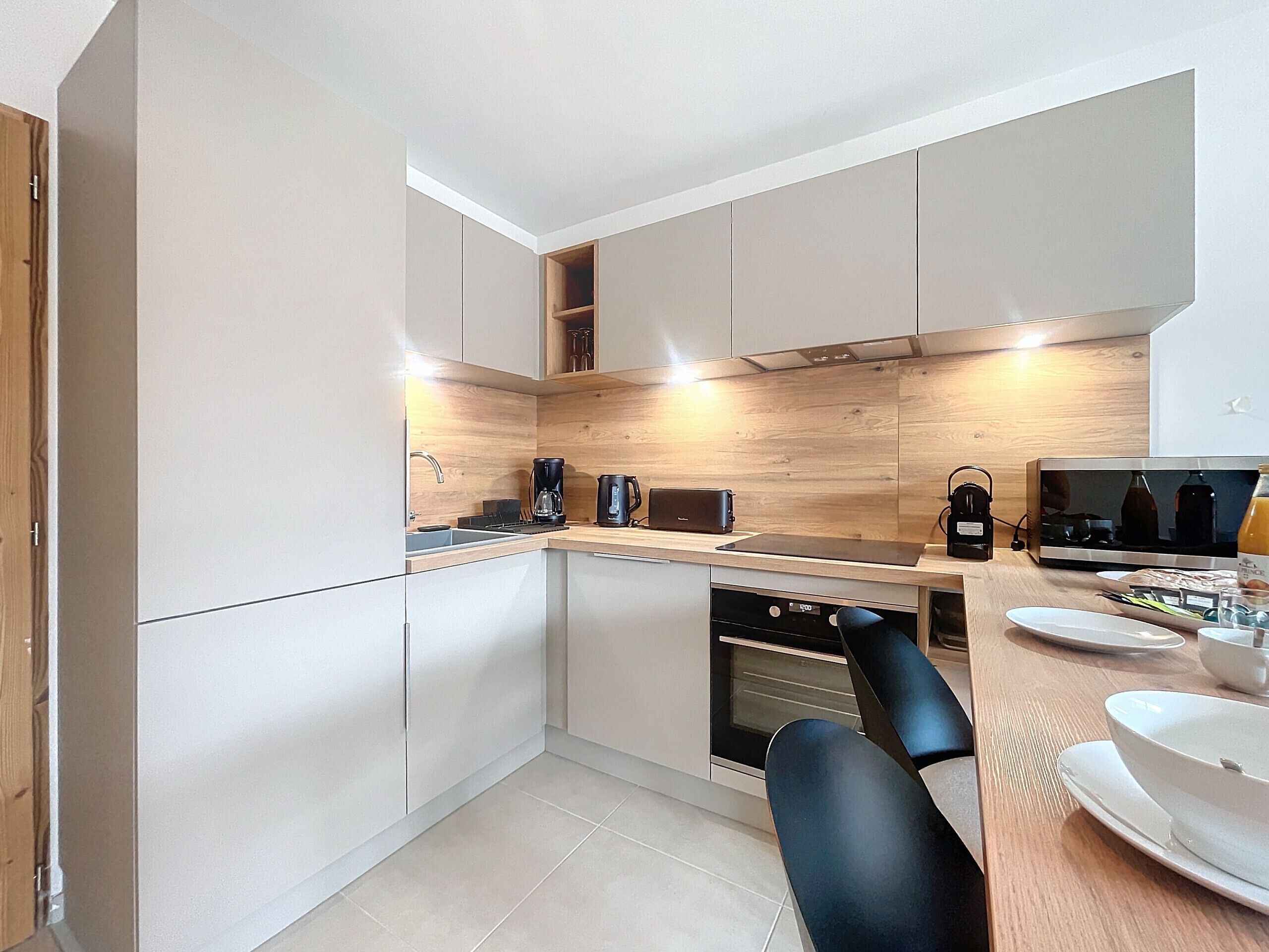 Una cocina moderna con gabinetes blancos, protector contra salpicaduras de madera y horno empotrado.