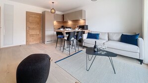 Un salon moderne avec un canapé, une table basse et des fauteuils. Il y a également un coin cuisine avec une table à manger et des chaises.
