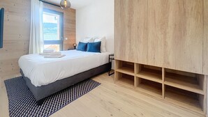 Une chambre moderne avec un lit, une armoire en bois, une table de chevet et une fenêtre avec des rideaux.