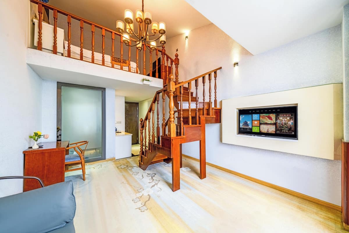 Ein geräumiger Wohnbereich mit einer Holztreppe, einem Wand-Fernseher und einem Essbereich.
