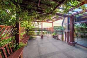 A covered outdoor area with a wooden bench, a glass railing, and a view of the sunset. - Boai Hotel International Hotel  (Shanghai)