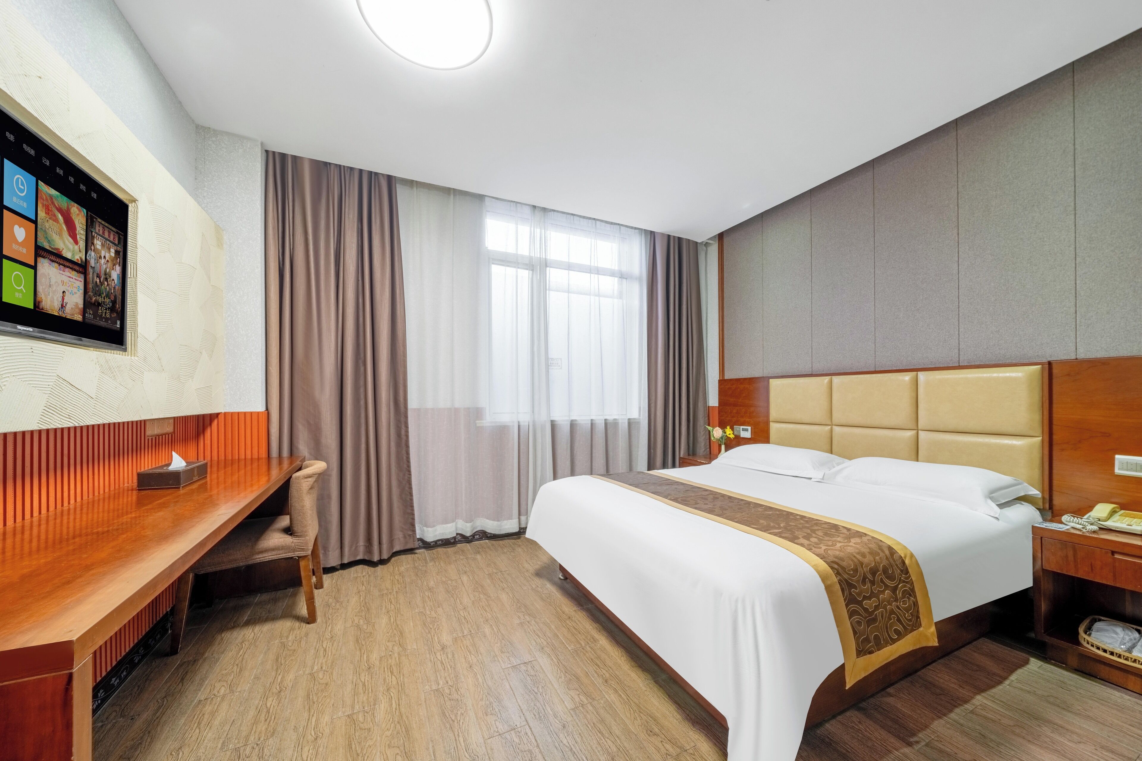Una habitación de hotel con una cama, un escritorio y un televisor montado en la pared.