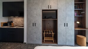 Une cuisine moderne avec des meubles de couleur sombre, un téléviseur encastré et un étagère en bois.