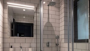 Une salle de bain moderne avec une douche à parois de verre, un lavabo blanc avec un miroir au-dessus et un carrelage décoratif.