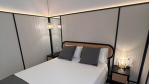 Una camera d'albergo moderna con un letto grande, un comodino con una lampada e un pavimento decorato.