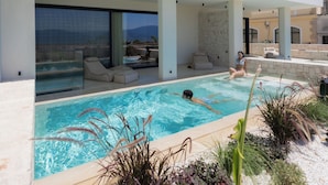 Ein modernes Haus mit Swimmingpool, großen Fenstern und Sitzgelegenheit im Freien.