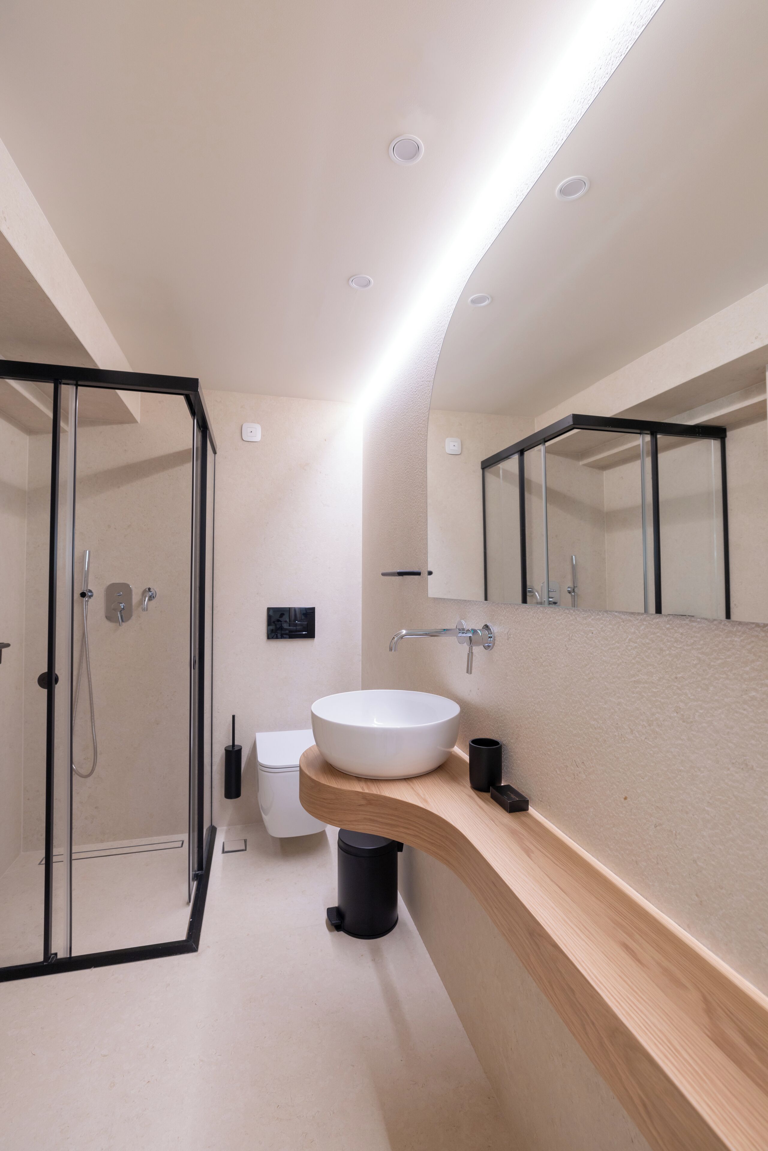 A modern bathroom with a glass shower enclosure, a white sink, and a large mirror.