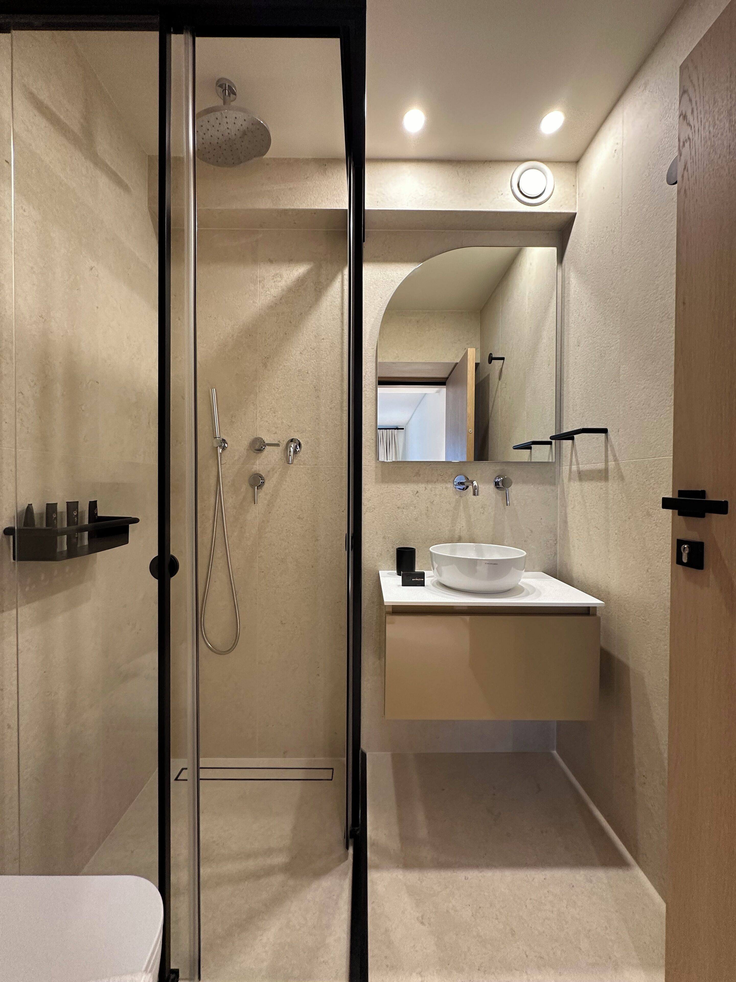 Une salle de bain moderne avec une douche à l’italienne en verre, un lavabo doté d’un grand bac et un miroir au-dessus du lavabo.