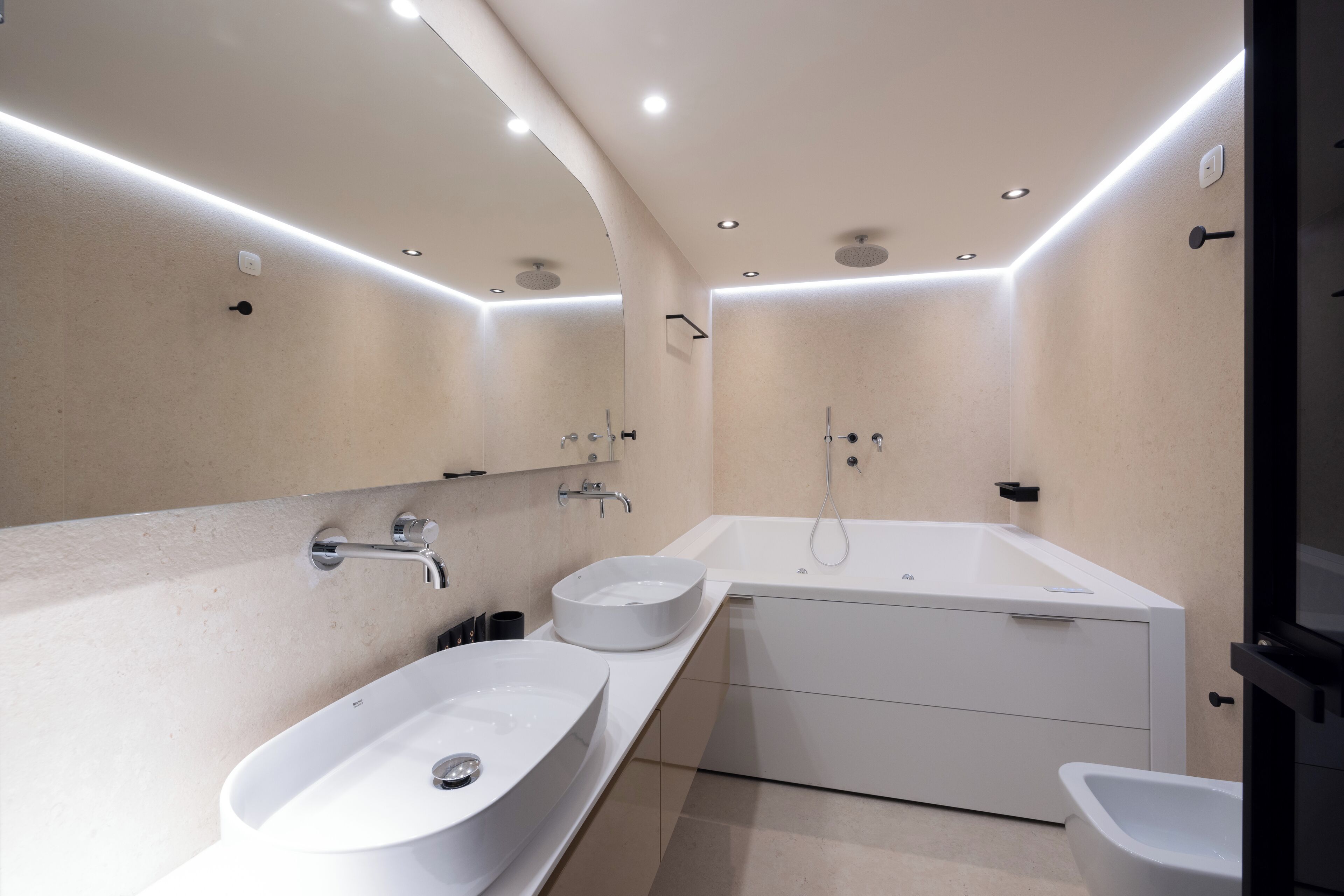 Ein modernes Badezimmer mit einem großen, ovalen Waschbecken, einer freistehenden Badewanne und einem separaten Handwaschbecken.