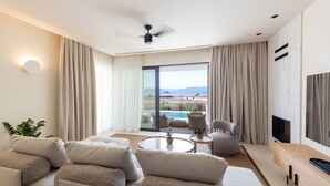 Ein modernes Wohnzimmer mit einer Sofagarnitur, einem Couchtisch, einem Fernseher und einem Deckenventilator.