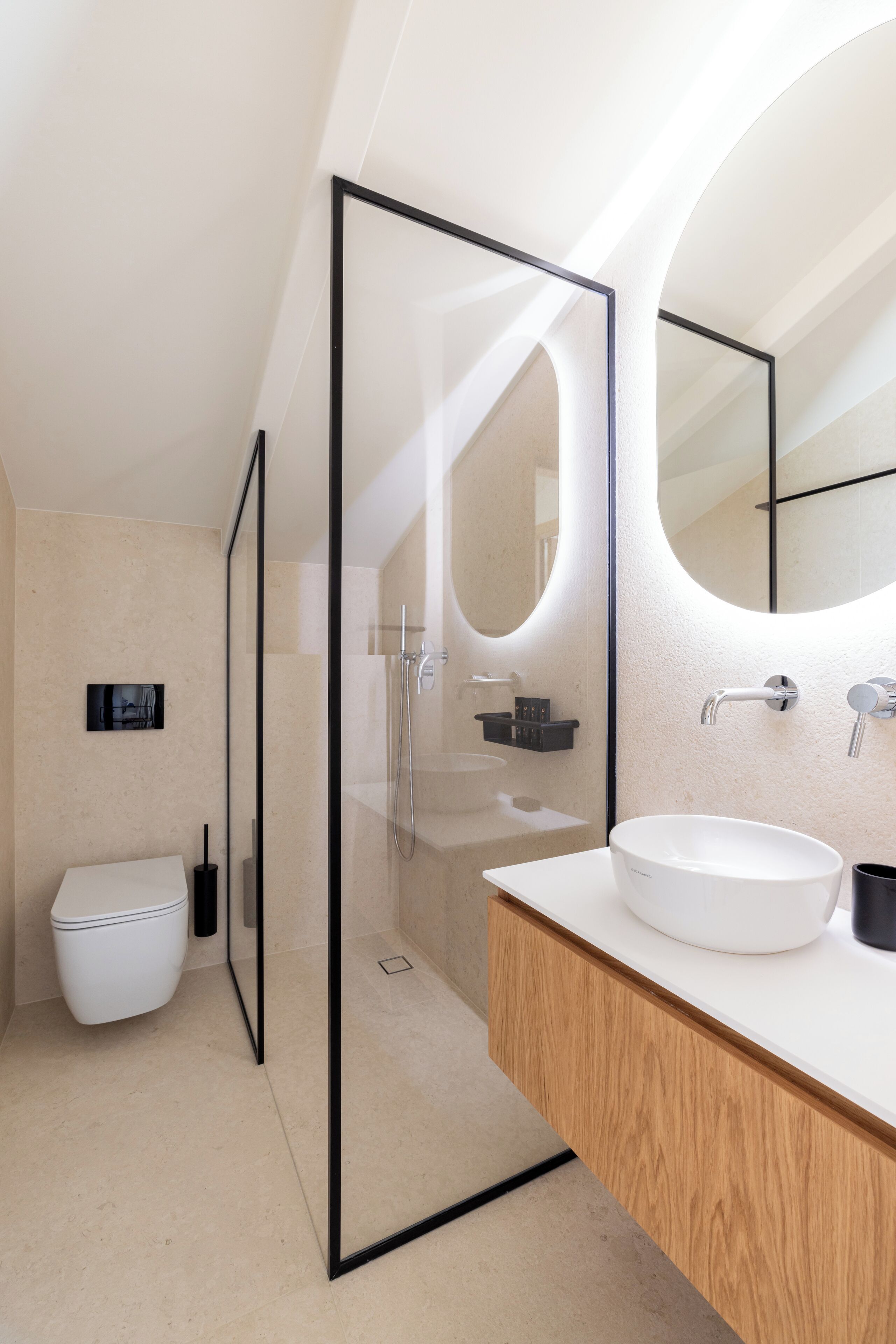 A modern bathroom with a glass-enclosed shower, a white sink, and a large mirror.