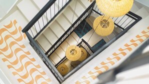 A modern interior with a staircase, black railings, and woven hanging lamps.
