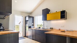A modern kitchen with dark cabinetry, a wooden countertop, and a yellow accent wall.