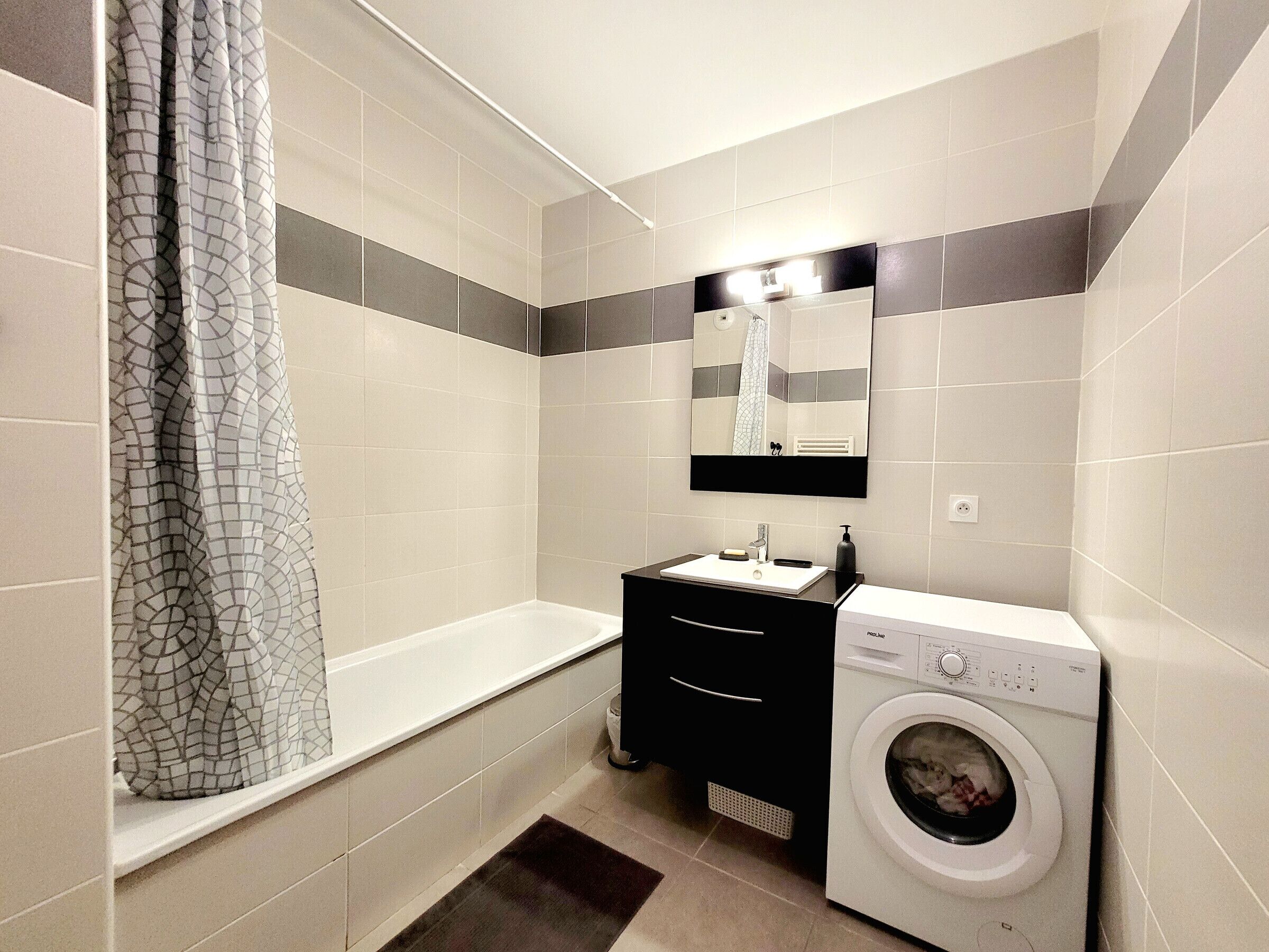 Uma casa de banho moderna com uma banheira, uma pia, um espelho e uma máquina de lavar roupa.