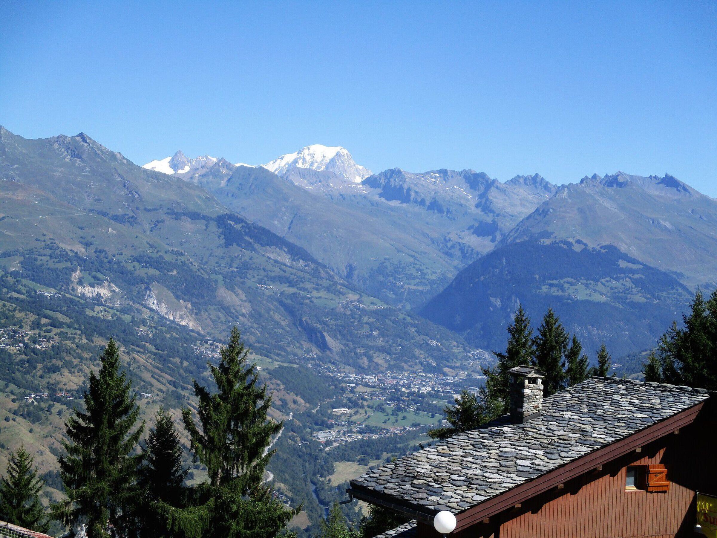 Vista de montaña con una cabaña de madera y cielo despejado.