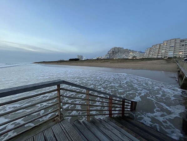 A beach with a wooden boardwalk leading to a sandy shore.