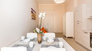 Ein moderner Essbereich mit Tisch für vier Personen, einer Vase mit weißen Blumen und einem weißen Schrank im Hintergrund.