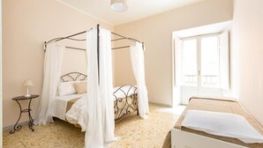 Ein Schlafzimmer mit einem Himmelbett, einem kleinen Nachttisch und einem Fenster mit Blick.