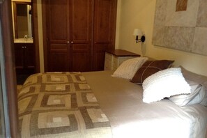 Une chambre à coucher comprenant un lit, une table de chevet, une lampe, une armoire et un miroir.